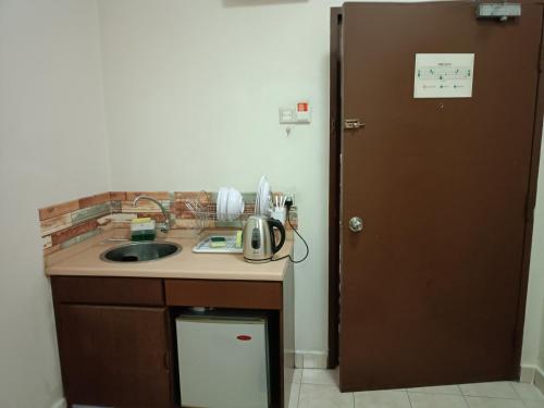 eine Küche mit einer Theke, einem Waschbecken und einer Tür in der Unterkunft Sofea Inn Bukit Merah - Suria A7245 in Simpang Ampat Semanggol