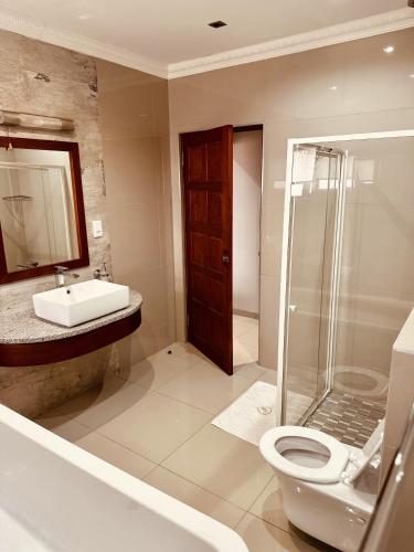 a bathroom with a toilet and a sink and a shower at Hotel Destiny in Ongwediva