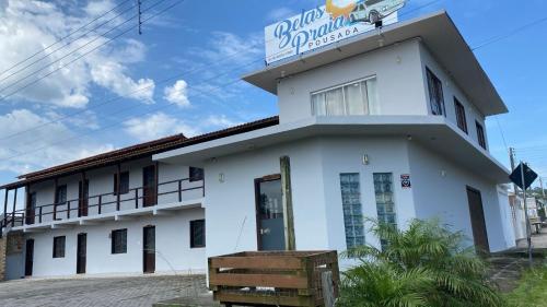 a white building with a sign on top of it at Pousada Belas Praia - Ribanceira in Imbituba