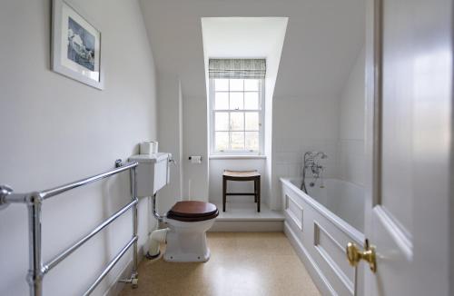 a white bathroom with a toilet and a window at Coulin Farmhouse in Kinlochewe