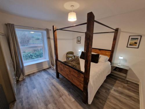 Over Torrs Cottage في New Mills: غرفة نوم بسرير خشبي مع أرضية خشبية