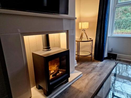 a living room with a fireplace with a tv above it at Over Torrs Cottage in New Mills
