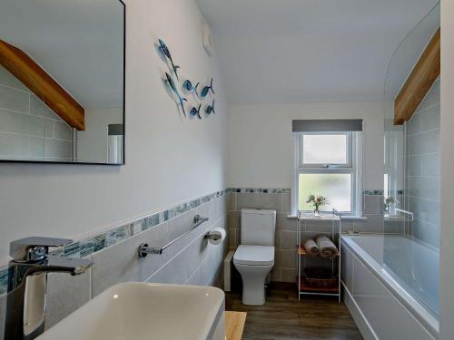 a bathroom with a sink and a toilet and a tub at 4 Bed in Bude CRESC in Bude