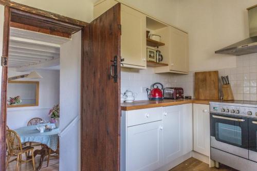 una pequeña cocina con armarios blancos y una mesa en The Granary, en Hartland