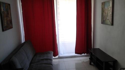 Zimmer mit einem Sofa und einem Fenster mit roten Vorhängen in der Unterkunft DESCANSO DEL VIAJERO 2 in Santiago