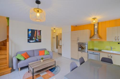 un salon avec un canapé bleu et une cuisine dans l'établissement La Balnéaire - à 50m de la plage, à Saint-Nazaire