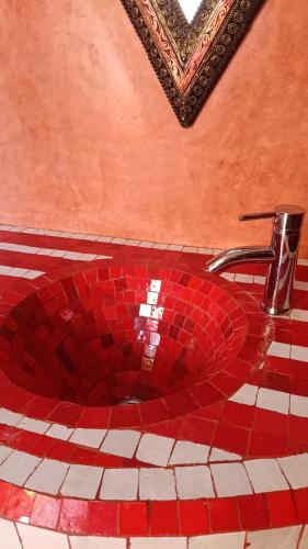 a red mosaic sink in a bathroom with a faucet at Les Bains de Fez Tara in Fès