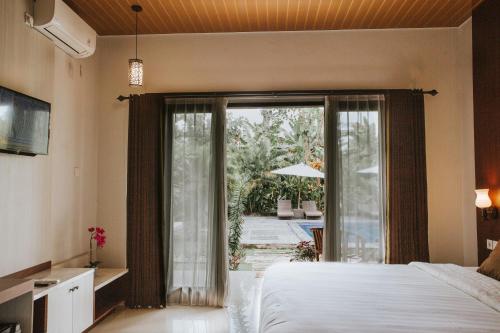 1 dormitorio con 1 cama y puerta corredera de cristal en Sawit Garden Cottages en Nusa Penida