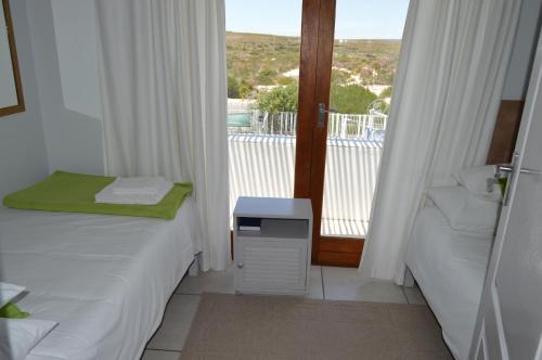 a room with two beds and a balcony with a view at Paters Haven Self-catering and B&B in Paternoster
