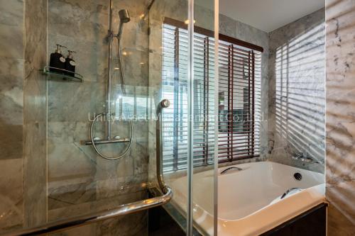 uma casa de banho com uma banheira e um chuveiro em vidro. em The Unity and The Bliss Patong Residence em Praia de Patong