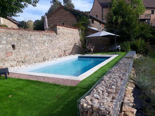 - une piscine dans une cour à côté d'un mur en pierre dans l'établissement Maison de 2 chambres avec jardin clos et wifi a La Vineuse, à La Vineuse