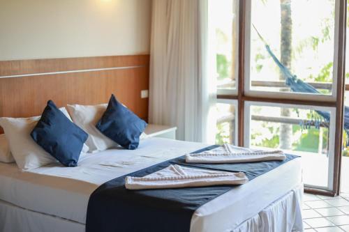 a bedroom with a bed with blue pillows and a window at Pontal da Ferradura in Búzios
