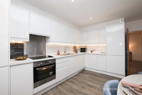 a white kitchen with white cabinets and appliances at Poole Quay, elegant apt, sleeps 4, Wi-Fi & parking - Carters Quay View in Poole