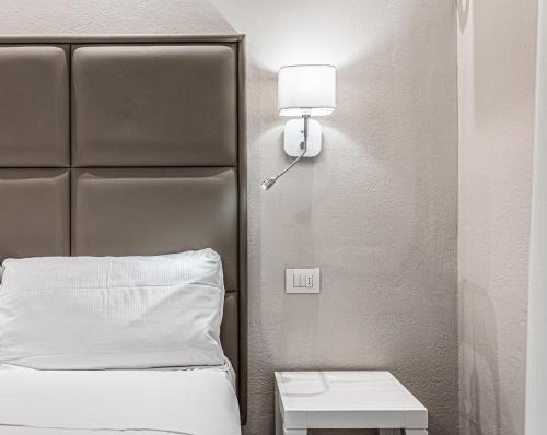 ミラノ・マリッティマにあるHotel Cubaのベッド1台、壁掛け電話が備わる客室です。
