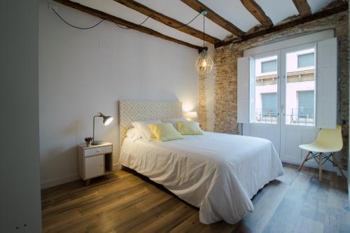 a bedroom with a white bed and a chair at Apartamentos Almada in Zaragoza