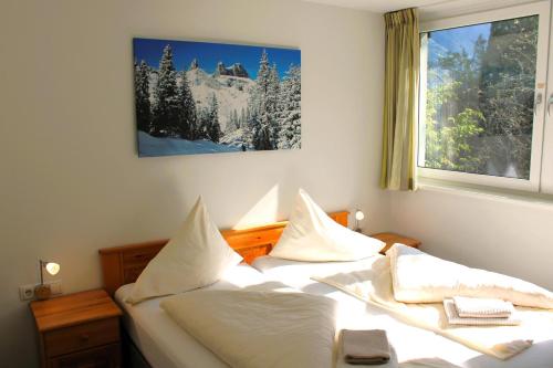 um quarto com uma cama com lençóis brancos e uma janela em Drei Türme 2 em Schruns