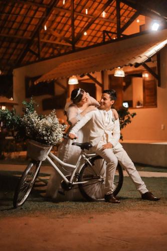 a bride and groom sitting on a bike at Pousada Yapara-Tyba in Japaratinga