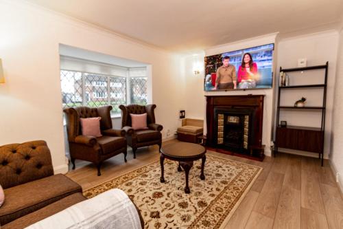 een woonkamer met een open haard en een flatscreen-tv bij 3BR Cottage in the Heart of Cheadle in Baguley