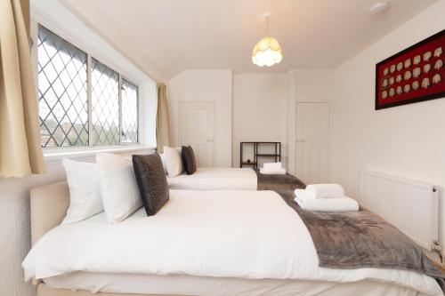 um quarto com 2 camas e uma janela em 3BR Cottage in the Heart of Cheadle em Baguley