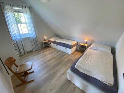 ein kleines Schlafzimmer mit 2 Betten und einem Stuhl in der Unterkunft Hus Hygge in Born