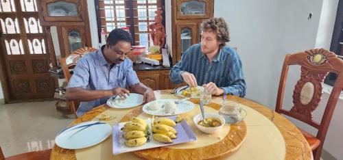 dos hombres sentados en una mesa comiendo comida en Pknhomestay kumily thekkady en Thekkadi