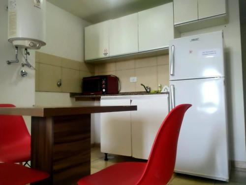 a kitchen with a white refrigerator and red chairs at Depto En Rosario in Rosario