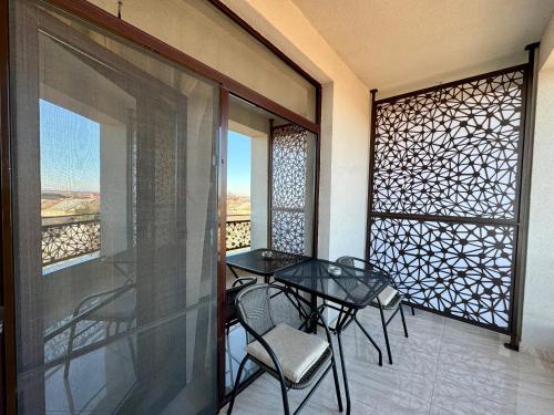 a balcony with a glass table and chairs on it at Escape Pensiune in Bechet