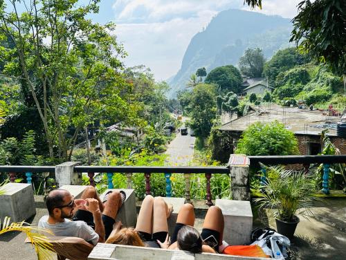 um grupo de pessoas deitadas num banco a olhar para uma montanha em Rock View Hostel Ella em Ella