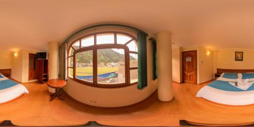 a room with two beds and a large window at Hotel Donde Marcelo in Baños
