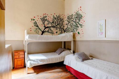 ein Schlafzimmer mit 2 Etagenbetten und einem Baumbild an der Wand in der Unterkunft Dante y compañia in Buenos Aires