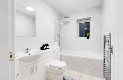 a white bathroom with a sink and a toilet and a tub at New Build Haven - Close to City Centre - Etihad in Manchester