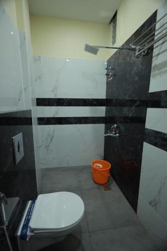 a bathroom with a toilet and an orange bucket at JEYAM HOLIDAY HOME in Kanyakumari