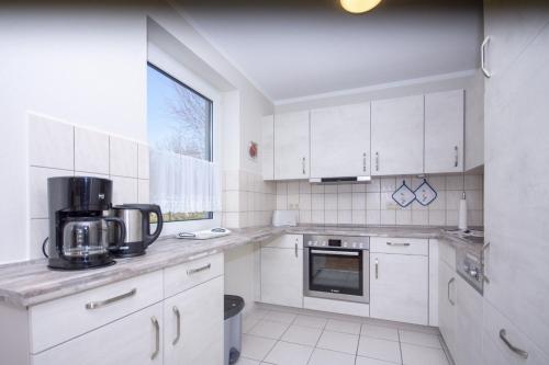 uma cozinha branca com armários brancos e uma janela em Haus Rügensonne, App 02 em Baabe