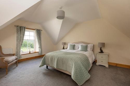 a bedroom with a bed and a chair and a window at Drumlanrig Mains Cottage in Thornhill