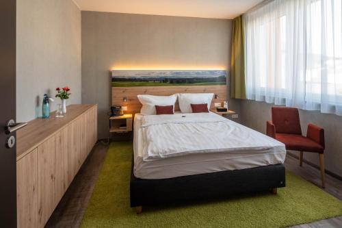 a bedroom with a large bed and a chair at Hotel Schlossberg Wehingen in Wehingen