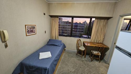 una camera con letto, scrivania e finestra di Edificio Presidente a Mendoza