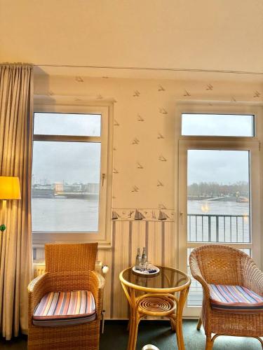 a room with two chairs and a table and two windows at Gästehaus Weserblick am Weser-Sandstrand in Berne