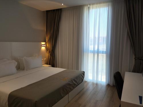 ein Hotelzimmer mit einem Bett und einem großen Fenster in der Unterkunft Metro Hotel Terminal in Tirana