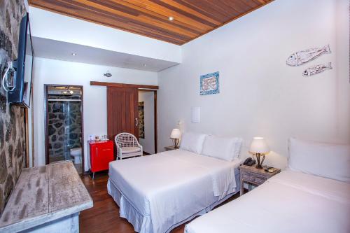 a bedroom with two beds and a table with two lamps at Barra do Piuva Porto Hotel in Ilhabela