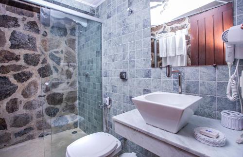 a bathroom with a toilet and a glass shower at Barra do Piuva Porto Hotel in Ilhabela