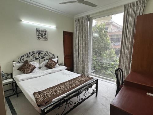 a bedroom with a bed and a large window at Pamposh Guest House, Gurgaon in Gurgaon