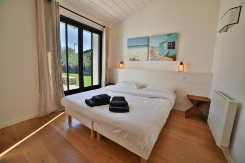 a bedroom with a bed with two black towels on it at Villa Madame - Pool - Near Beach and Golf in Les Portes