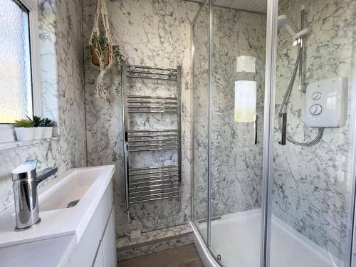 a bathroom with a shower and a tub and a sink at Little Haven, one bed chalet in Dartmouth, Devon in Dartmouth