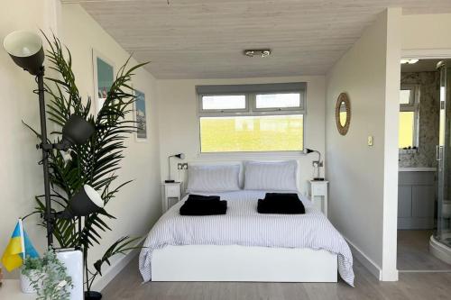 a bedroom with a white bed with black pillows at Little Haven, one bed chalet in Dartmouth, Devon in Dartmouth