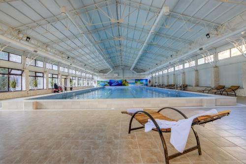 Mountain View Hot Spring Resort في Alamedin: مسبح وكراسي في مبنى كبير