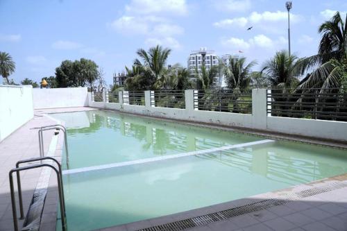 een zwembad met blauw water voor een hek bij Infinity Penthouse with Pool, Sauna, Gym in Rajkot