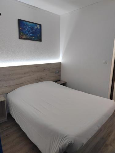 a white bed in a room with a picture on the wall at Alpha Hotel in Bouafle