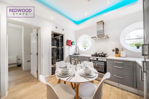 a kitchen with a white table and chairs in a kitchen at Brand New 1 Bed 1 Bath, Modern Town Center Apartment, Netflix By Redwood Stays in Aldershot