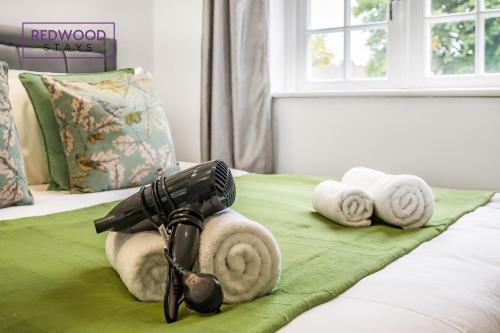 un secador de pelo sentado en una cama con toallas en BRAND NEW, 1 Bed 1 Bath, Modern Town Center Apartment, FREE Parking, Netflix By REDWOOD STAYS, en Aldershot