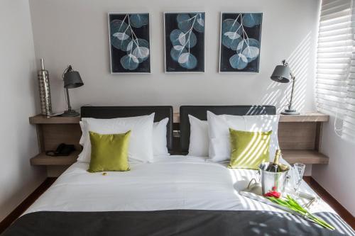 1 dormitorio con 1 cama con sábanas blancas y almohadas verdes en Hotel Pasko, en Santiago